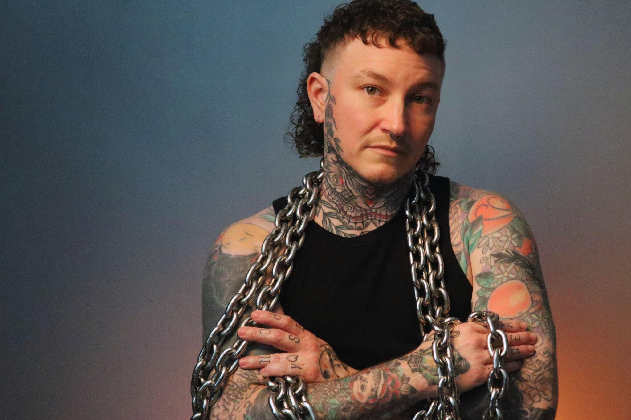 Headshot of Alec with chains draped over both shoulders.